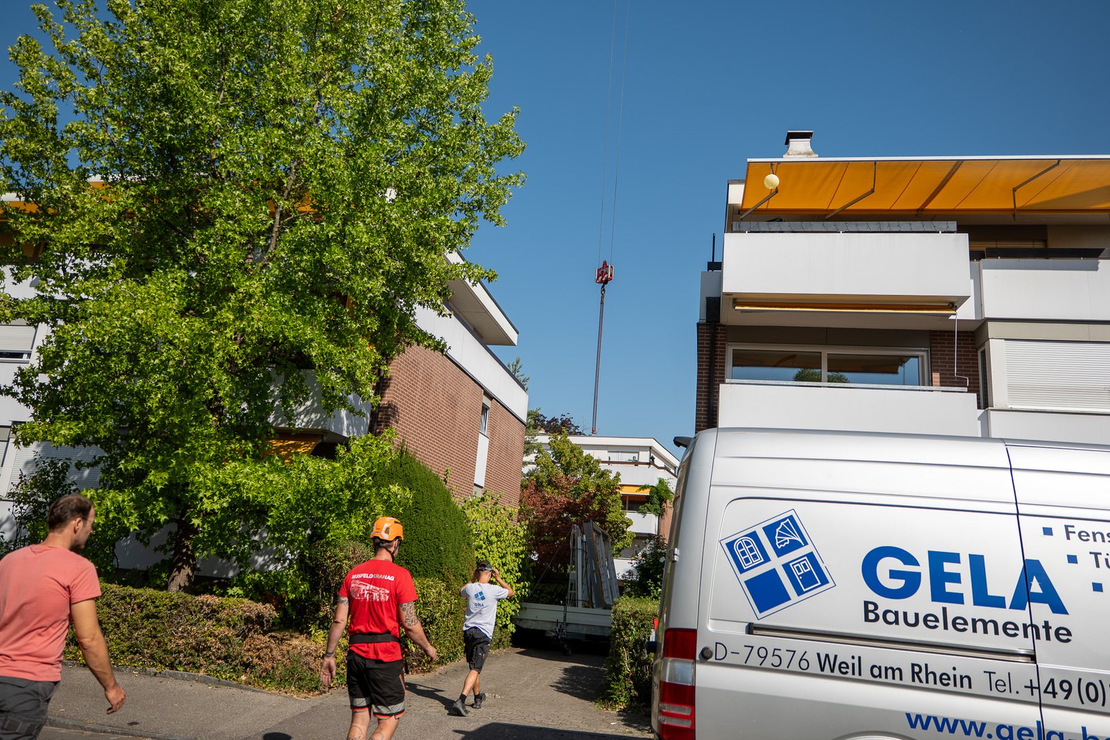 GELA-Transporter und Team vor dem Mehrfamilienhaus